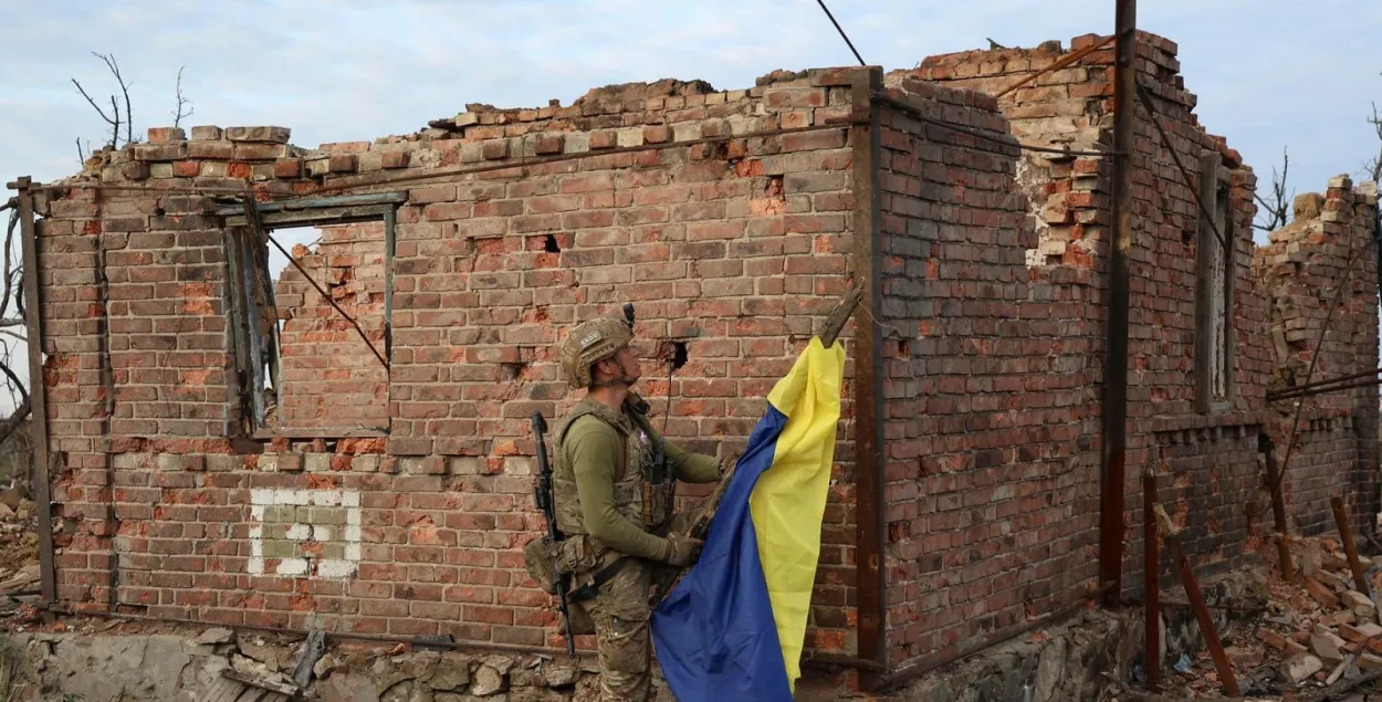 Украинский солдат устанавливает государственный флаг в освобождённом населённом пункте под Бахмутом
