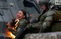 Спецназовцы помогают женщине-полицейской, на которой загорелась одежда / Reuters