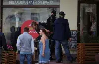 Милиционеры в штатском выводят людей из кафе, в котором разбили дверь / Reuters​
