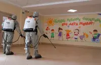 Военнослужащие Минобороны в защитных костюмах проводят дезинфекцию в Боровлянской школе/ Reuters