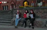 Девушки с пустыми листами возле костёла / Кадр из видео​